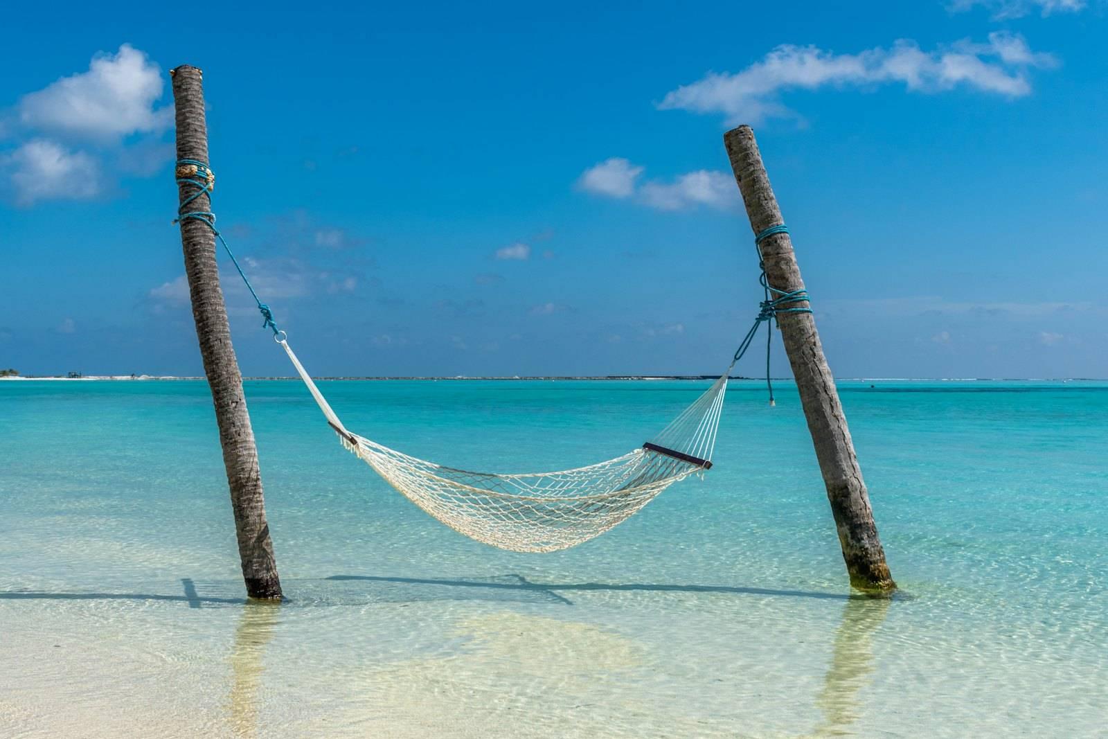 A hammock hanging between two wooden poles in the ocean