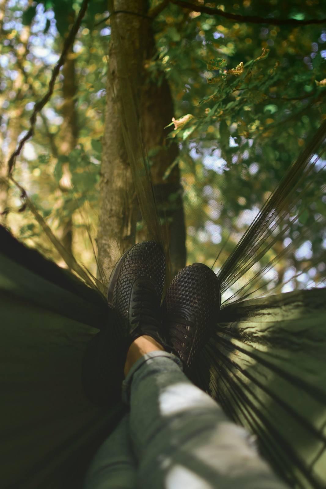 Person on camping hammock tied on tree